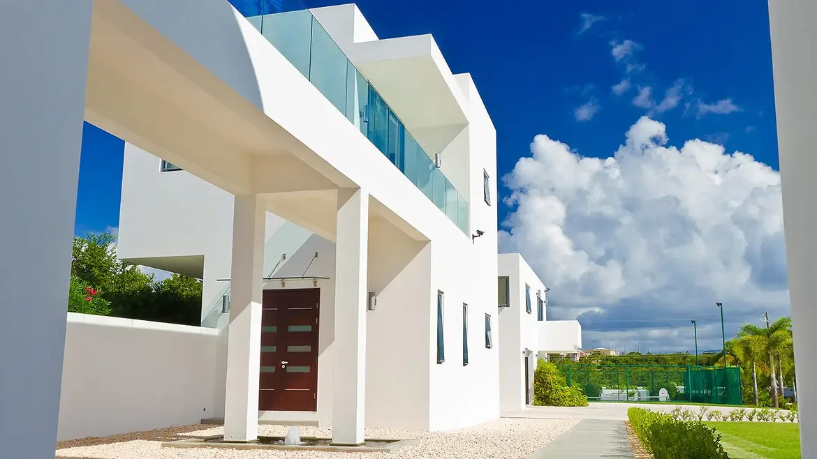 Walk-in shower with dark brown tiles and chrome shower panel overlooking a tropical valley and blue ocean.