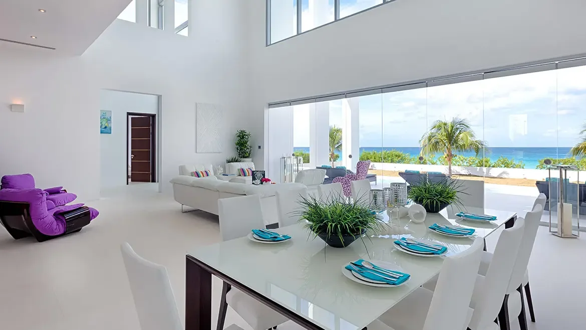 White outdoor patio with exercise bike and potted plant overlooking a coastal town and green mountains.