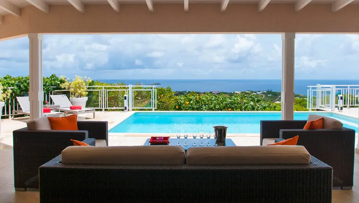 Retreat to the sun-drenched covered terrace of Villa Au Coeur du Rocher, where plush wicker seating frames a sparkling infinity pool and endless Caribbean horizons. Sip chilled refreshments as trade winds carry the scent of tropical blooms, with panoramic ocean views stretching to the horizon—a private sanctuary for effortless island luxury.                                                                                                                                               +
 