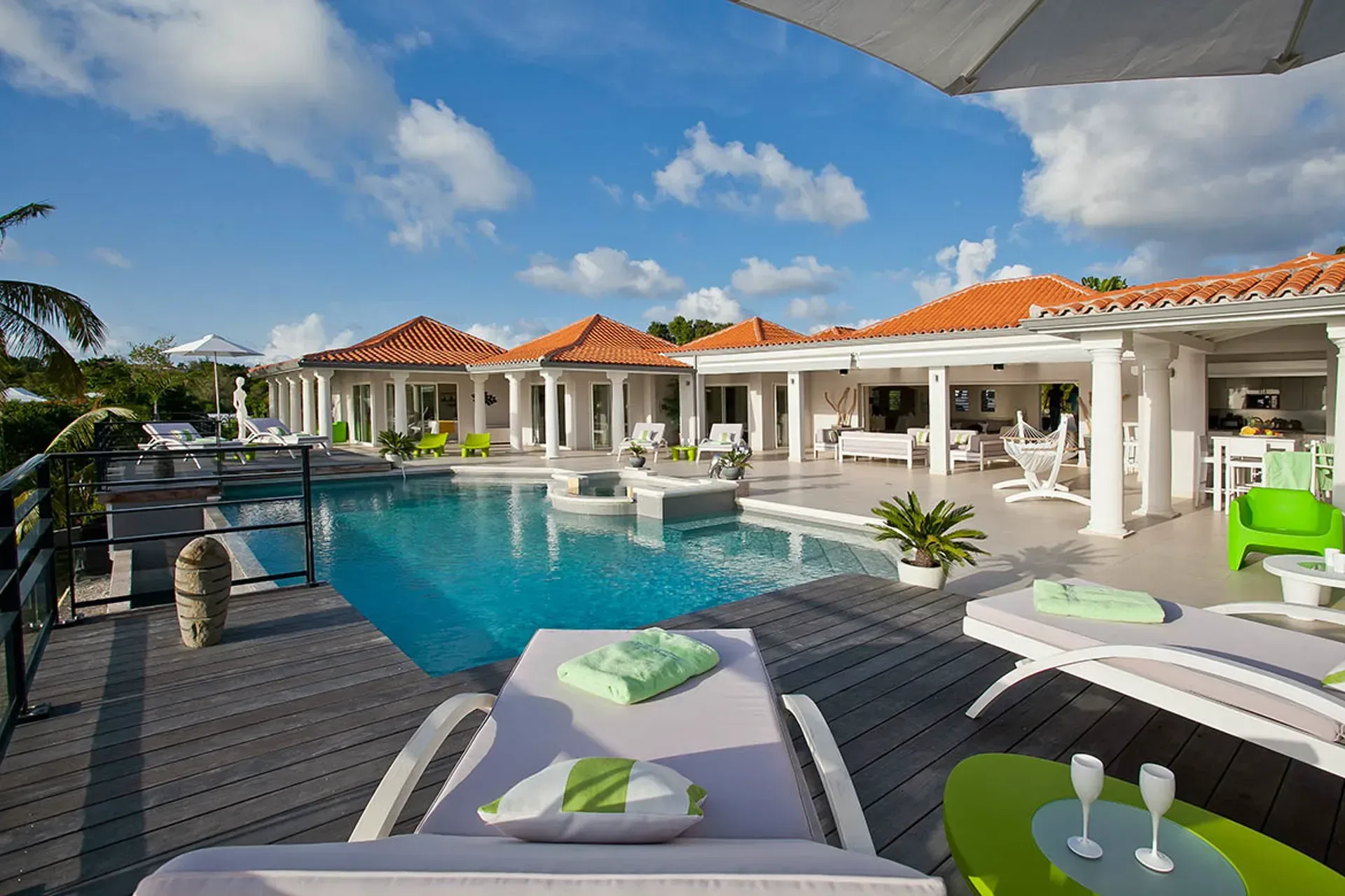 Pool and terrace with Mediterranean villa and terracotta roofs.