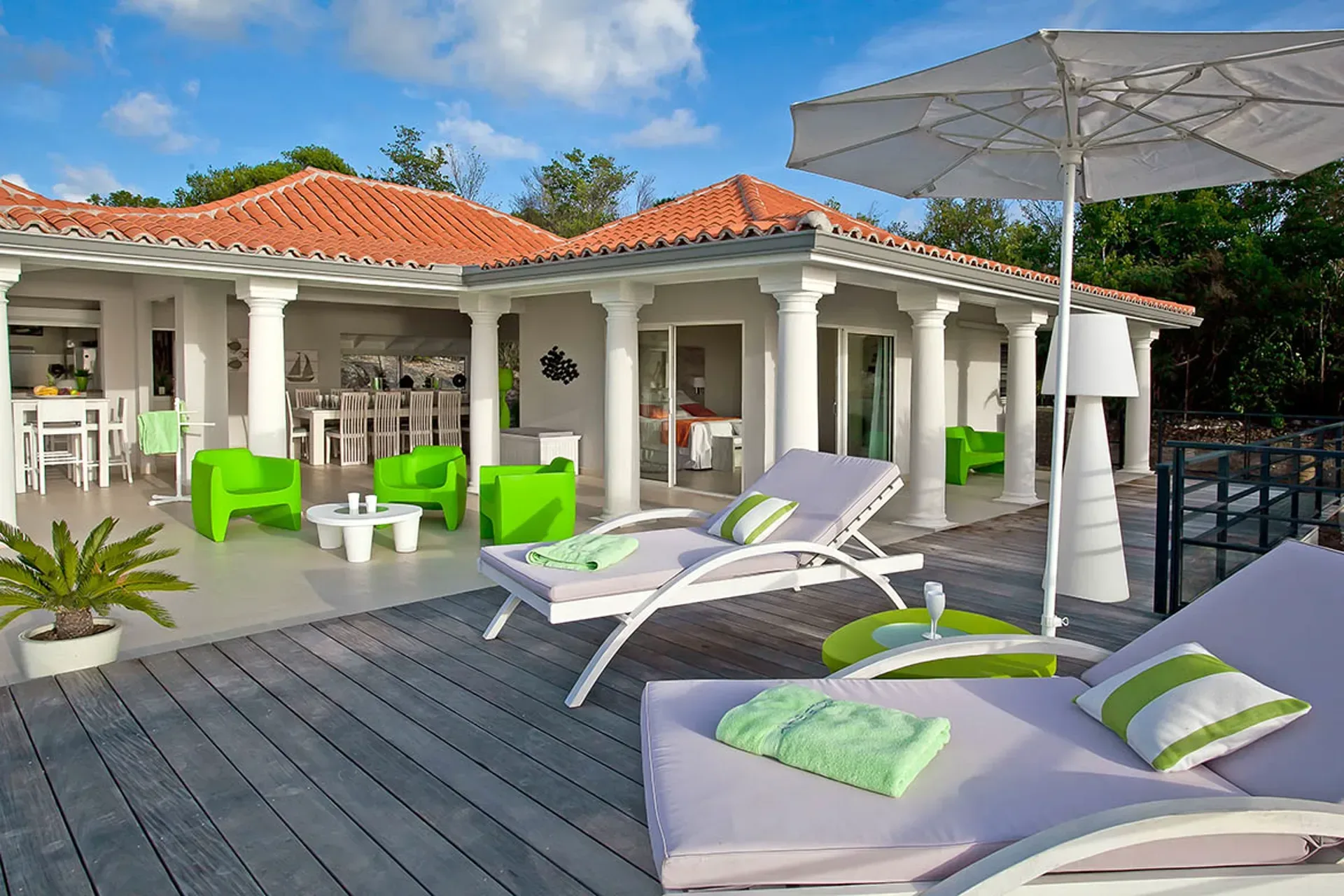 Covered terrace with loungers and green modern outdoor furniture.