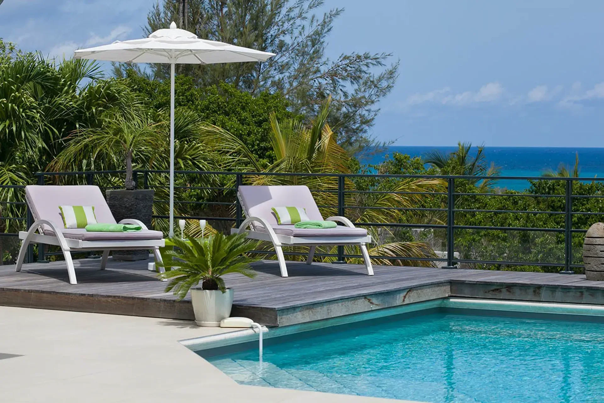 Terrace with loungers and pool overlooking tropical gardens.