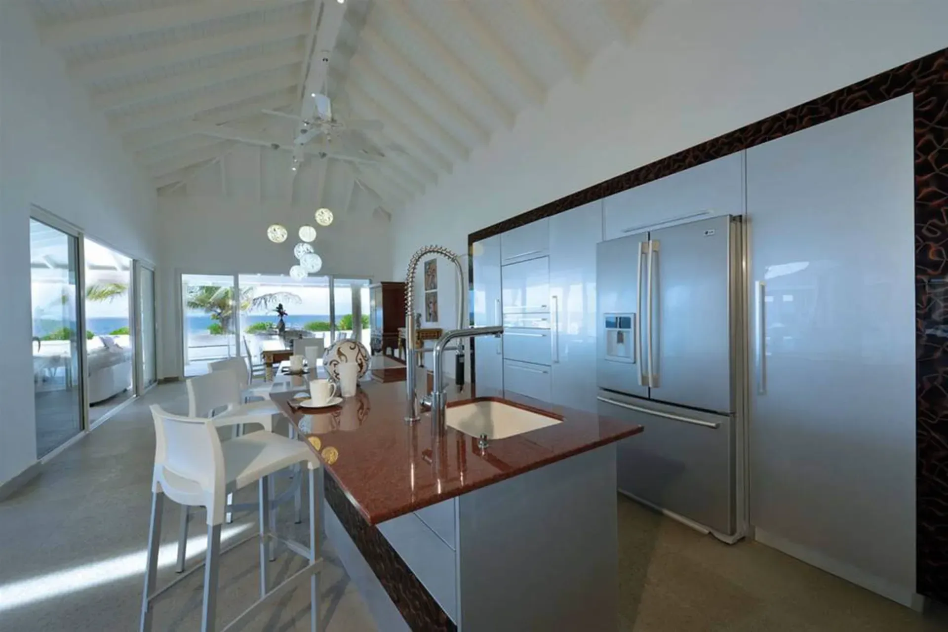 Cook in style with a sleek red granite island, stainless appliances, and ocean views through floor-to-ceiling glass doors.